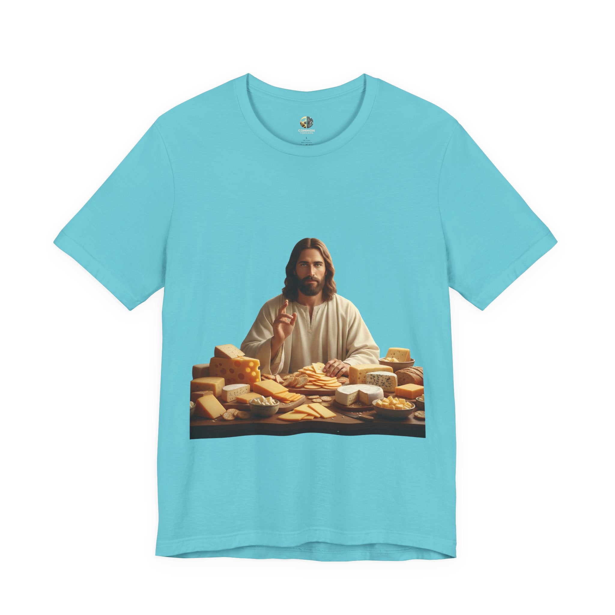 Turquoise T-shirt featuring a graphic of Jesus in traditional robes seated before a table filled with various cheeses, referencing a ‘Cheeses Sliced’ wordplay