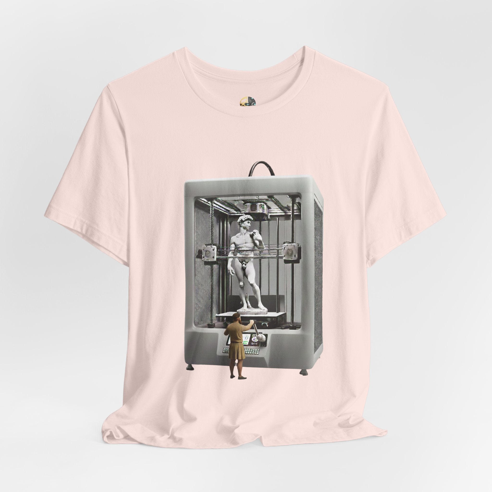 Soft pink T-shirt featuring a graphic of Michelangelo’s David statue being created inside a large 3D printer, with Michelangelo standing at the controls