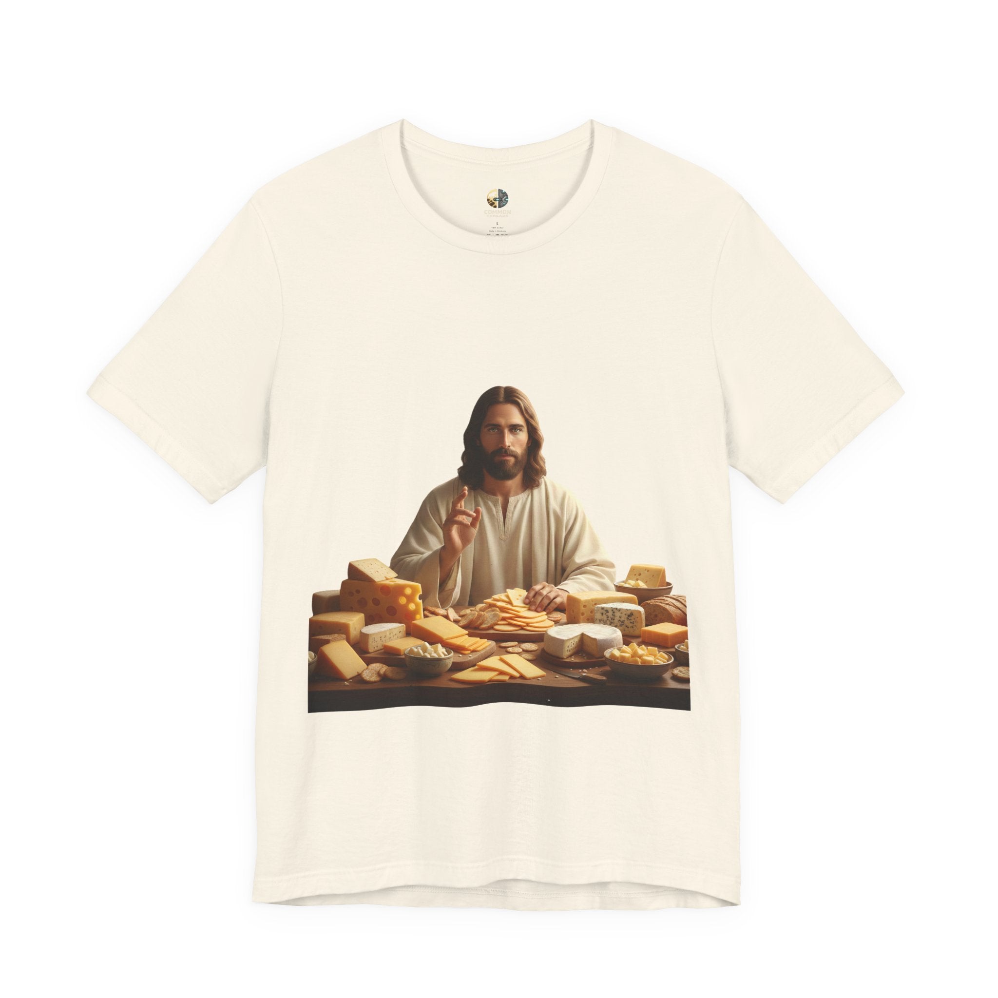 Natural color T-shirt featuring a graphic of Jesus in traditional robes seated before a table filled with various cheeses, referencing a ‘Cheeses Sliced’ wordplay