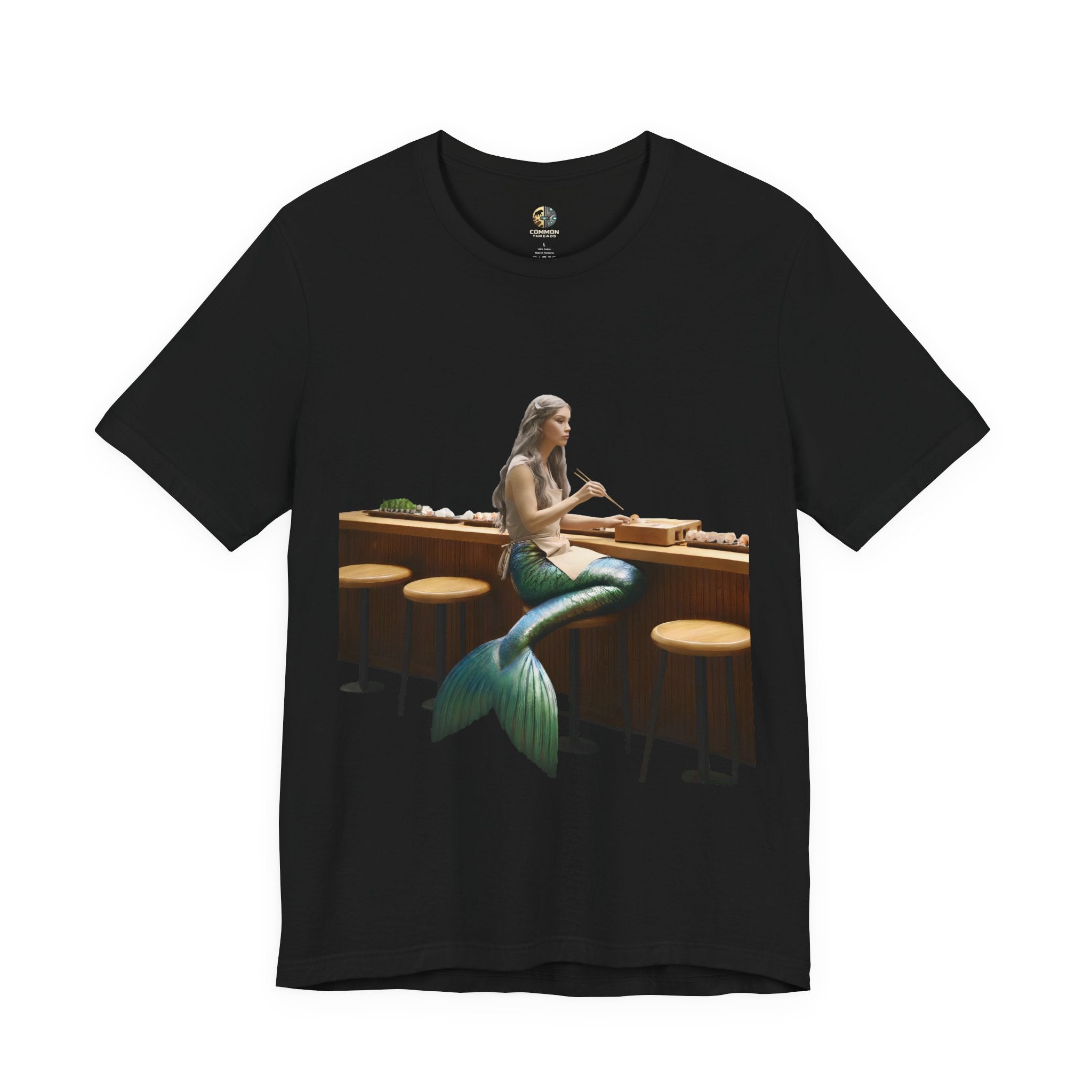 Black T-shirt with graphic of a mermaid wearing a chef’s apron sitting at a sushi bar and eating sushi with chopsticks