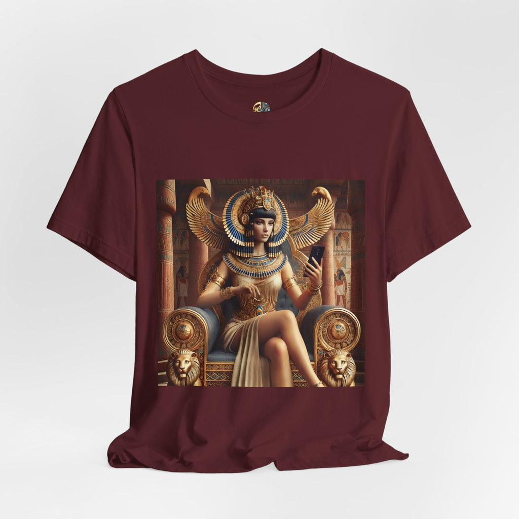 Maroon color T-shirt featuring a graphic of Cleopatra wearing an ornate headdress and gold jewelry, seated on a throne and holding a smartphone for a selfie, with temple architecture in the background