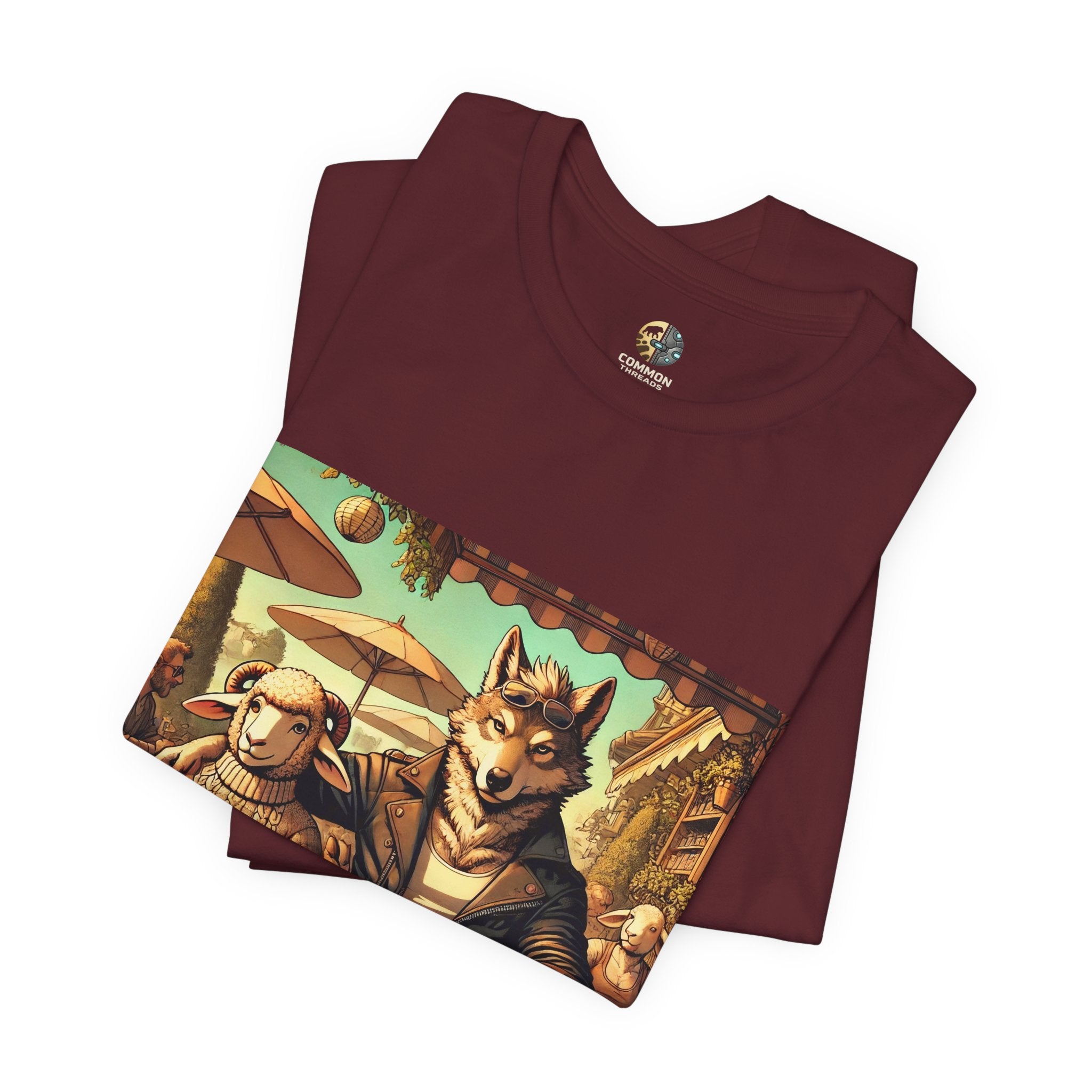 Folded maroon color T-shirt featuring an anthropomorphic wolf and lamb seated at a café table in warm, painterly style