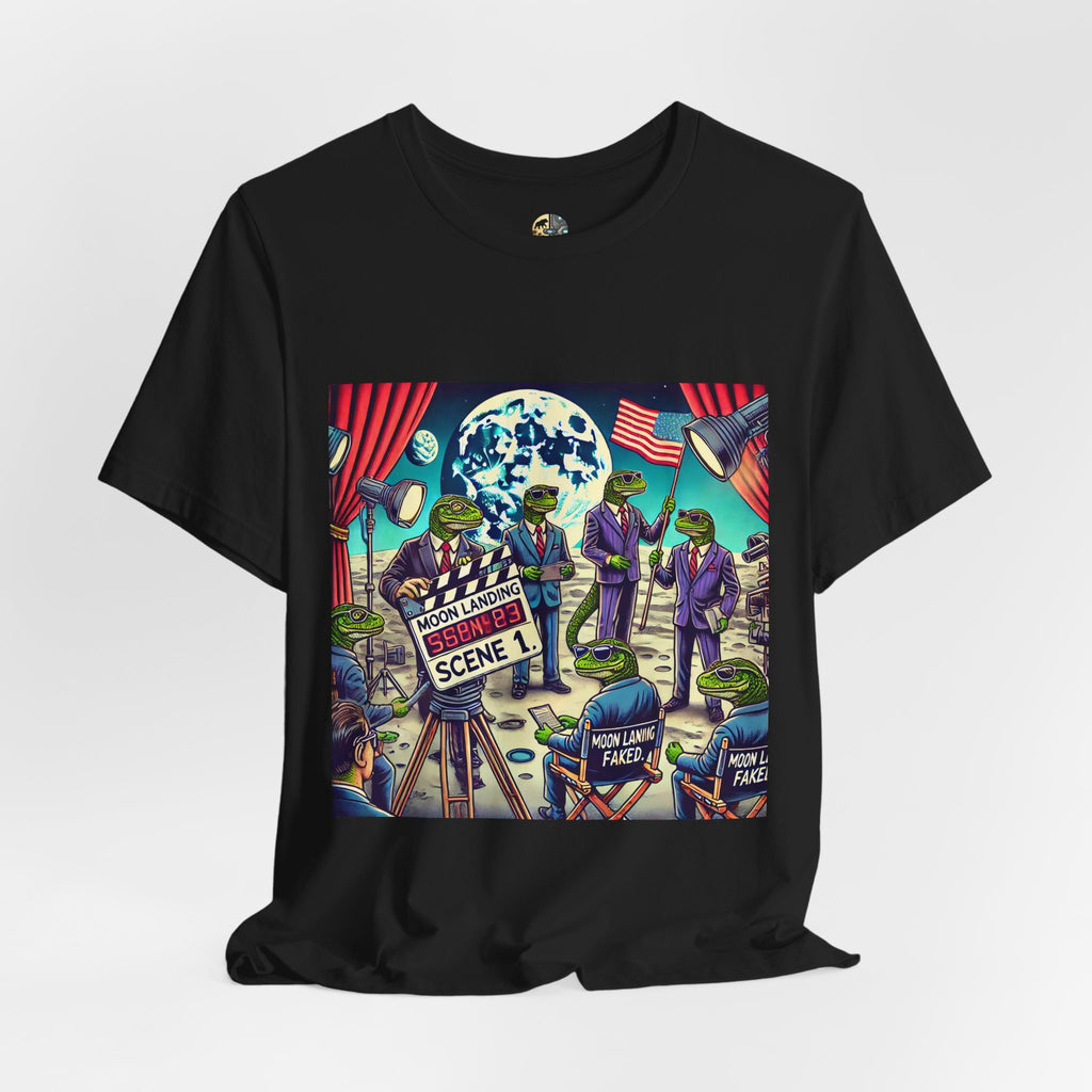 Black T-shirt featuring a graphic of lizard people in suits on a movie set staging a moon landing scene, with studio lights and a clapperboard