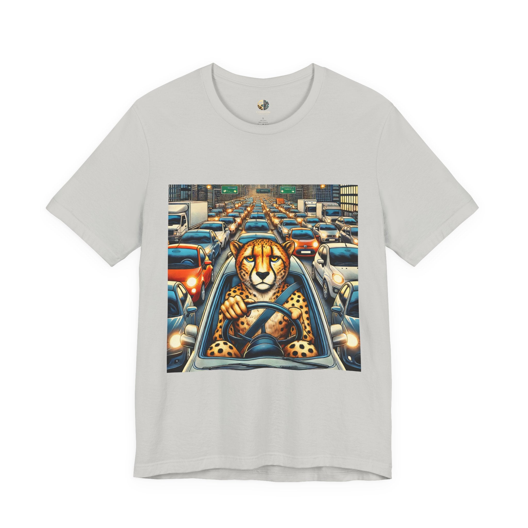 Silver T-shirt featuring a graphic of a cheetah sitting in the driver’s seat of a car stuck in heavy city traffic