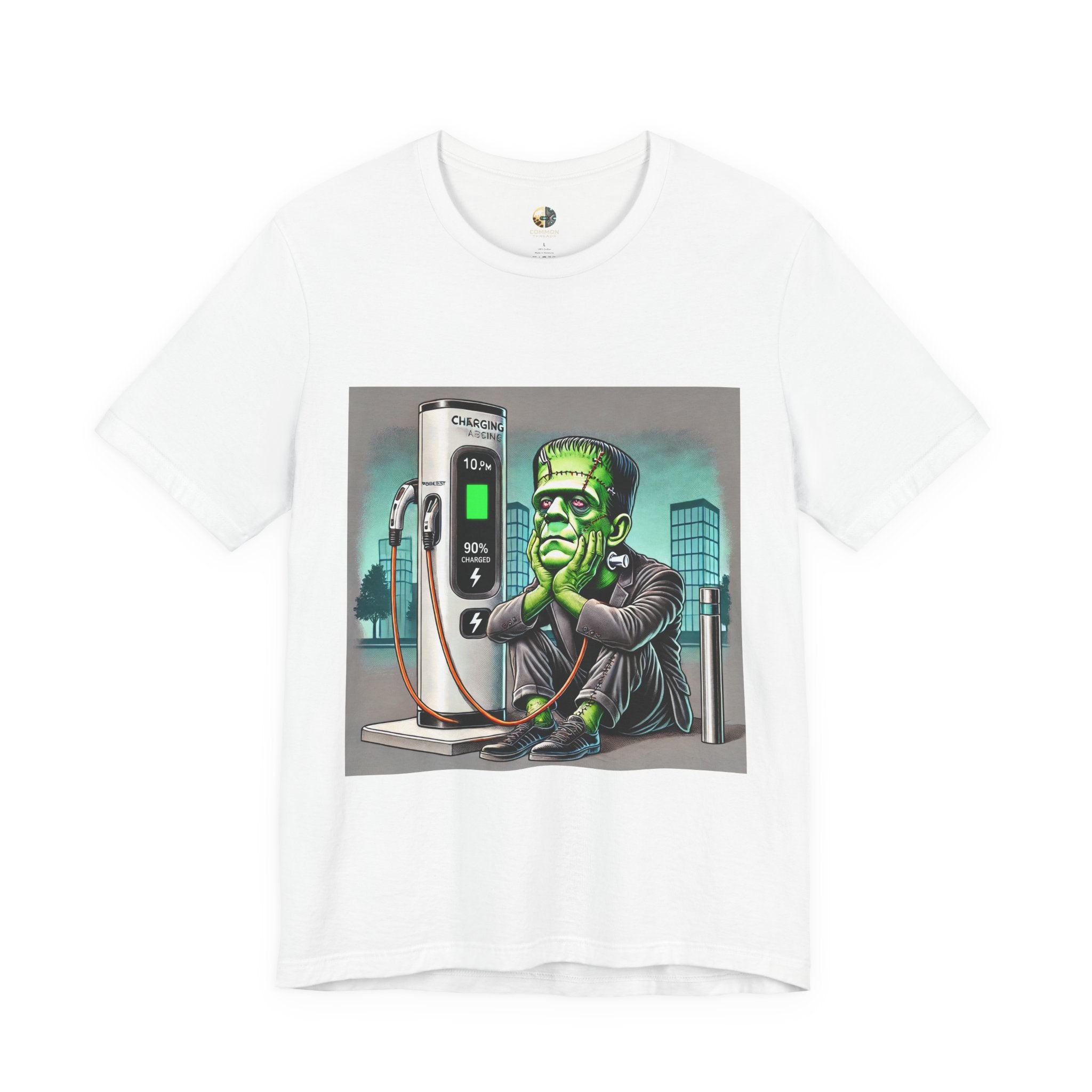 White T-shirt featuring a graphic of Frankenstein’s monster sitting at an electric charging station, plugged in and waiting for the charge to complete, with office buildings in the background