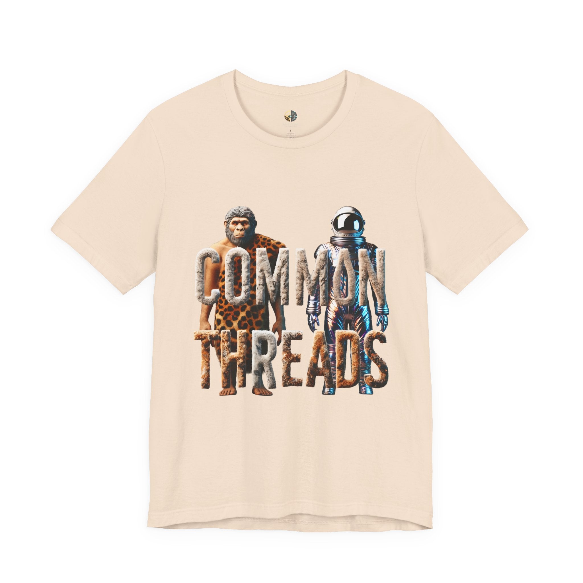 Soft creme T-shirt featuring a graphic of a caveman in animal pelts standing beside a chrome-plated astronaut, with the text ‘Common Threads‘