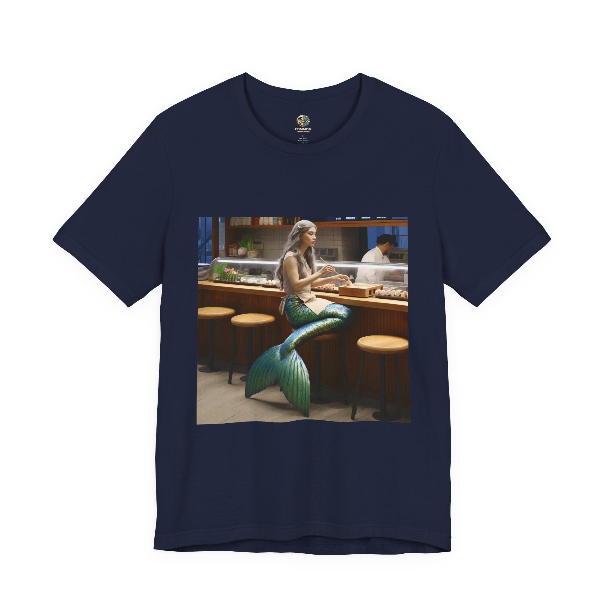 Navy blue T-shirt featuring a graphic of a mermaid wearing a chef’s apron sitting at a sushi bar and eating sushi, with a chef behind the counter