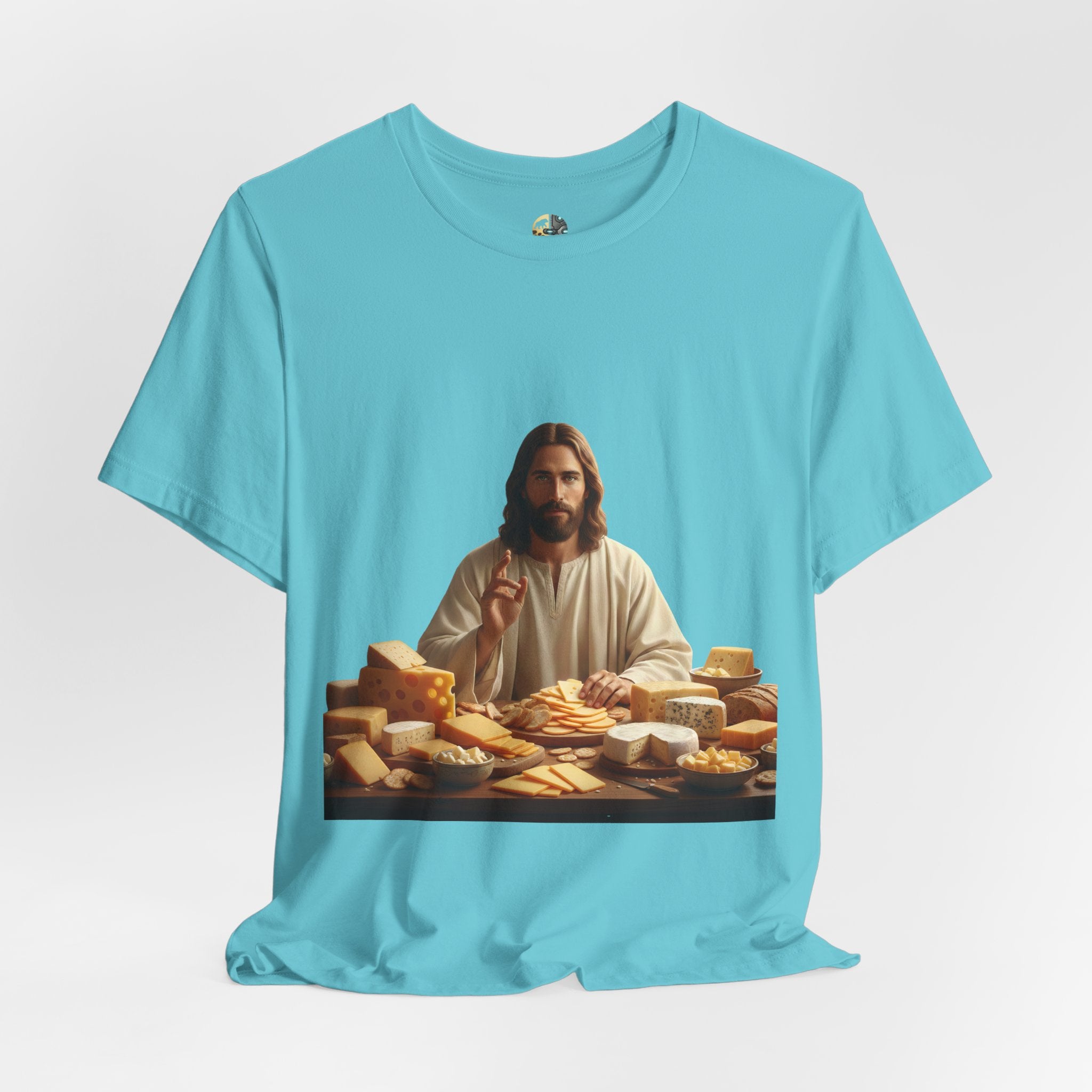 Turquoise T-shirt featuring a graphic of Jesus in traditional robes seated before a table filled with various cheeses, referencing a ‘Cheeses Sliced’ wordplay