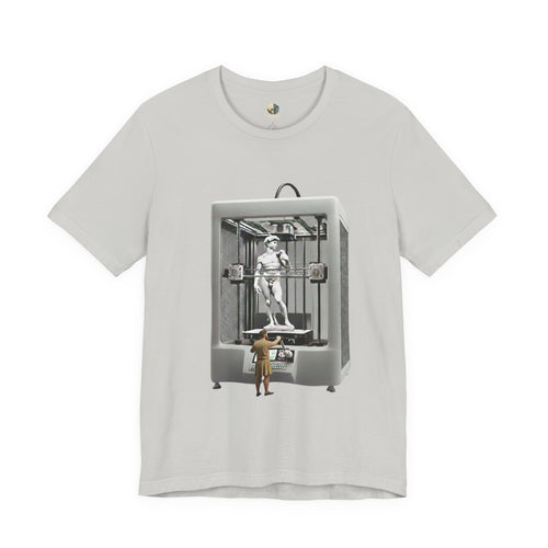 Silver T-shirt featuring a graphic of Michelangelo’s David statue being created inside a large 3D printer, with Michelangelo standing at the controls