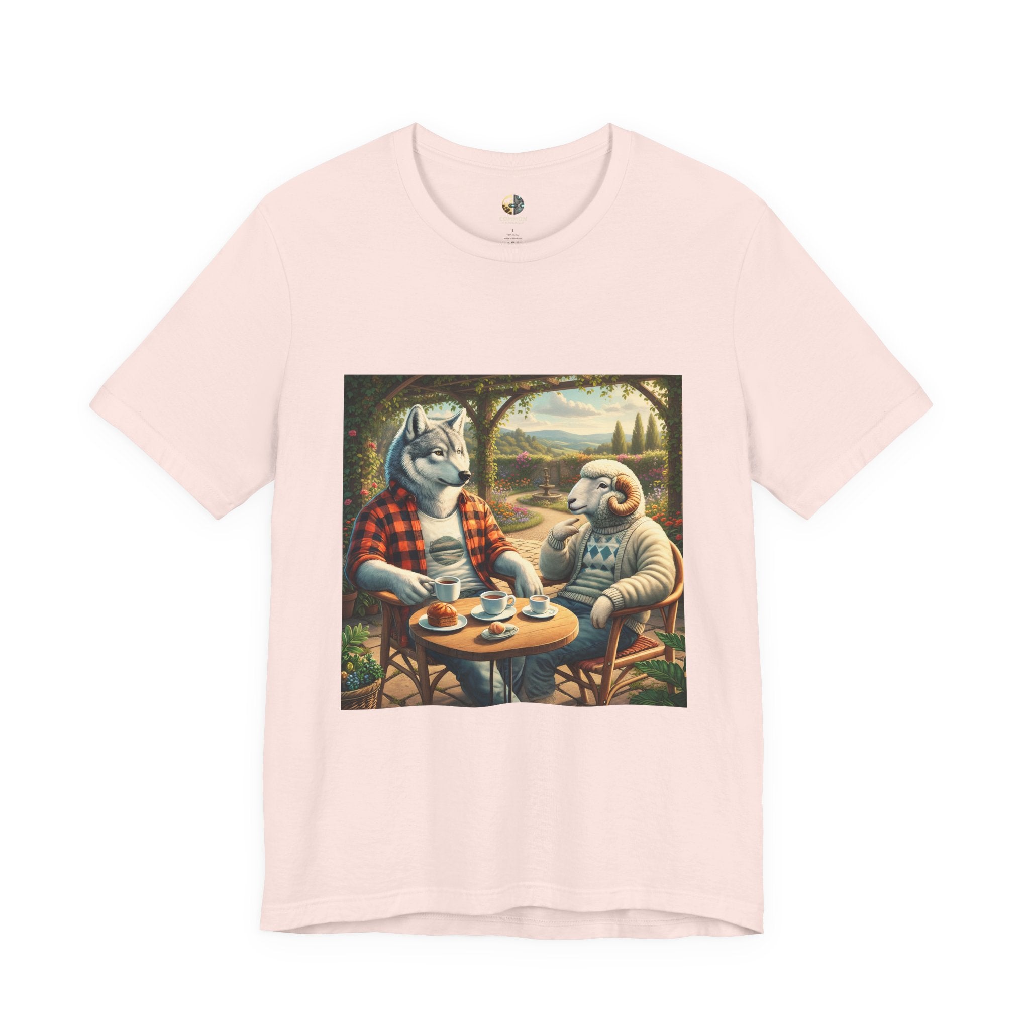 Soft pink color T-shirt featuring a graphic of a wolf in a flannel shirt and a ram in a patterned sweater sitting at a café table drinking coffee on a porch