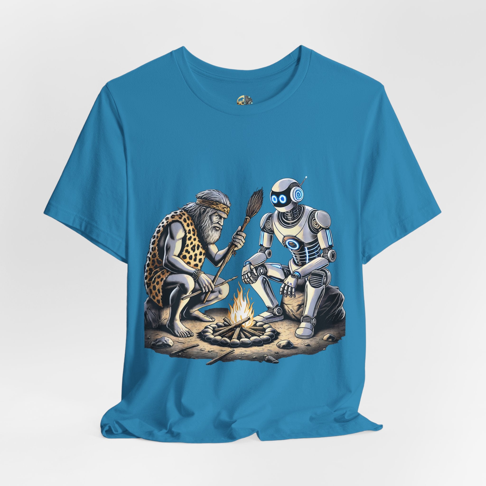 Aqua blue T-shirt featuring a graphic of a bearded caveman in a leopard-print pelt sitting by a campfire with a futuristic robot