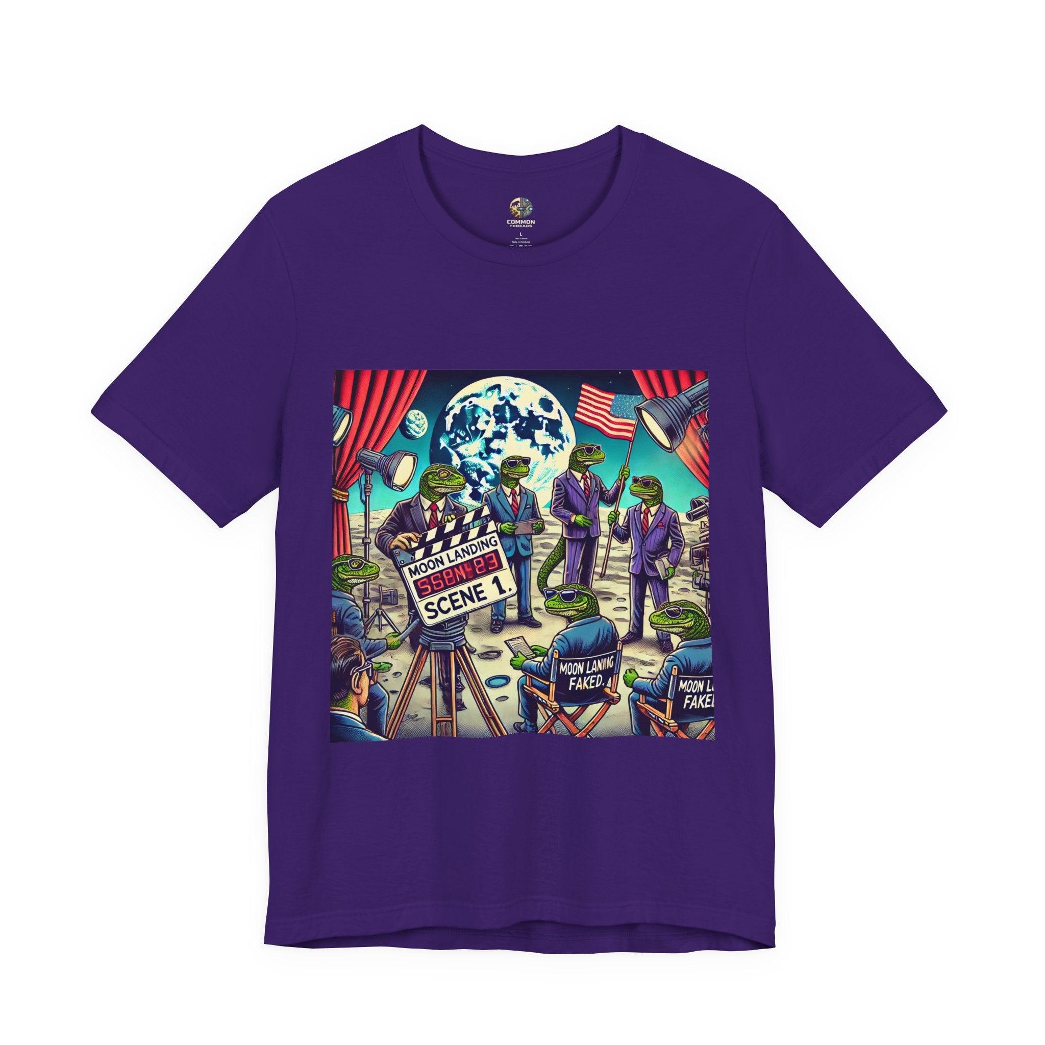 Purple T-shirt featuring a graphic of lizard people in suits on a movie set staging a moon landing scene, with studio lights and a clapperboard