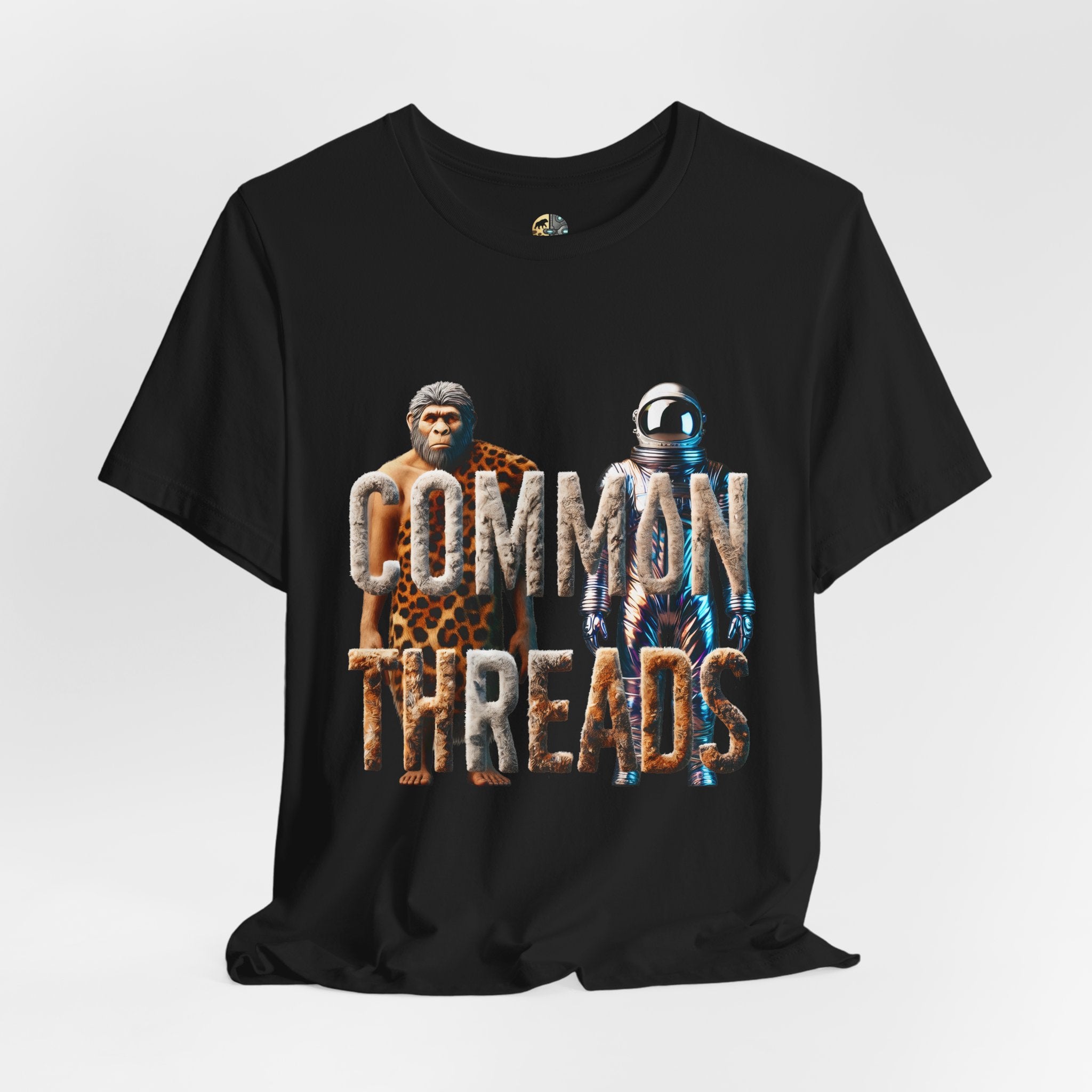 Black T-shirt featuring a graphic of a caveman in animal pelts standing beside a chrome-plated astronaut, with the text ‘Common Threads‘