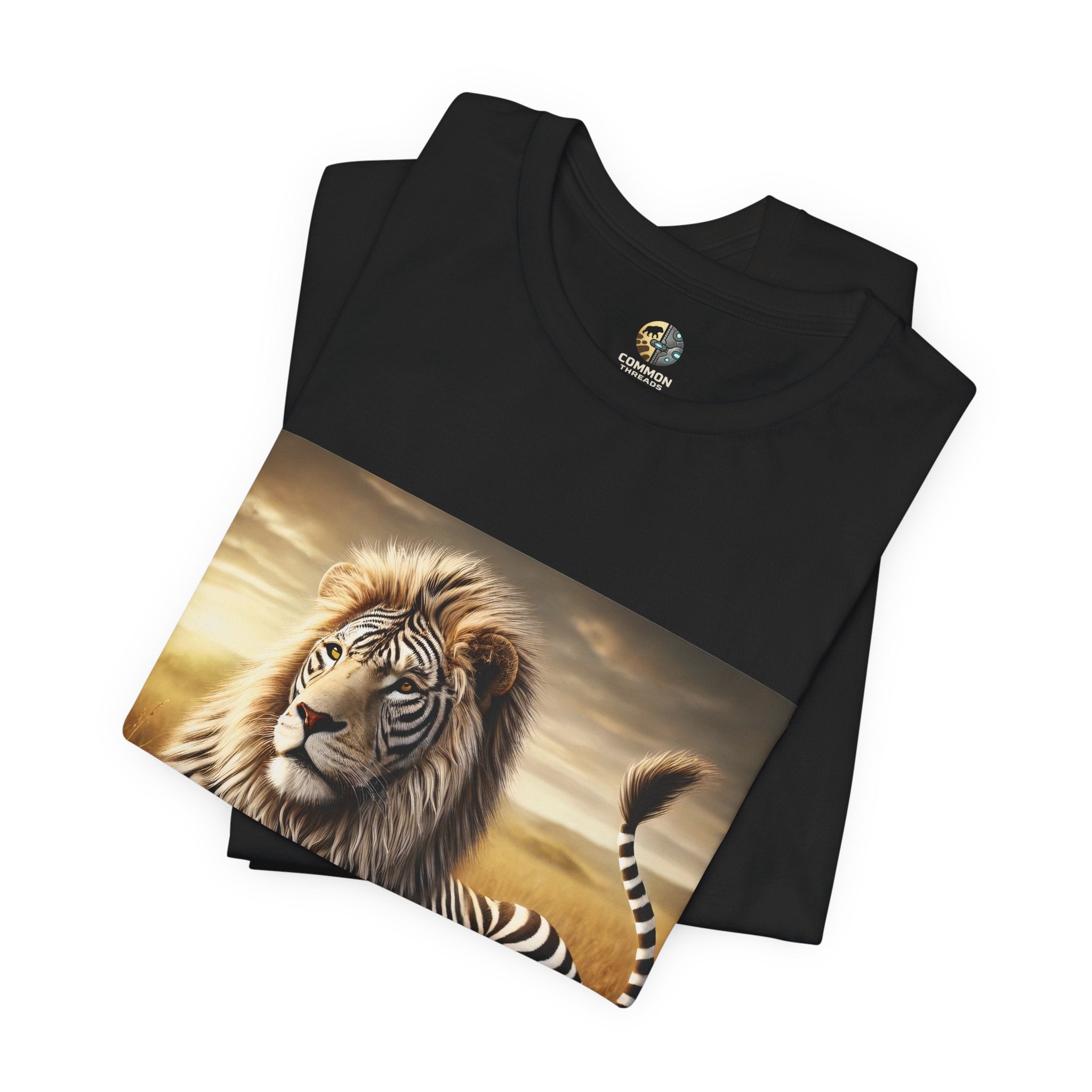 Folded black T-shirt featuring a lion with distinctive zebra-like stripes lying on dry savanna grass under a clear sky