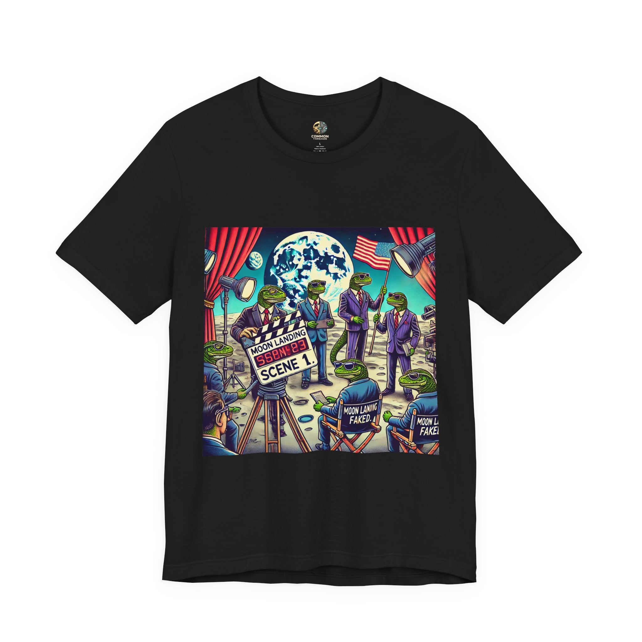 Black T-shirt featuring a graphic of lizard people in suits on a movie set staging a moon landing scene, with studio lights and a clapperboard