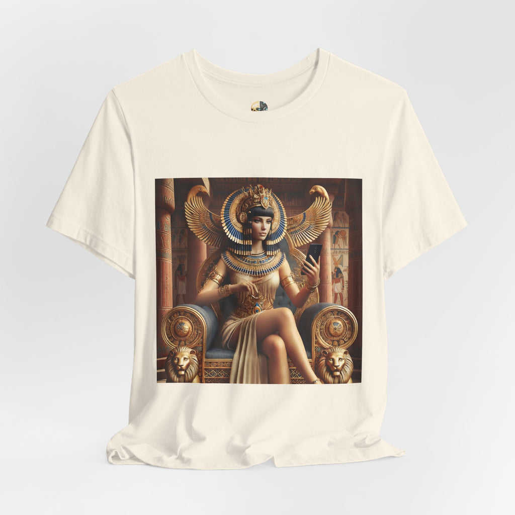 Natural color T-shirt featuring a graphic of Cleopatra wearing an ornate headdress and gold jewelry, seated on a throne and holding a smartphone for a selfie, with temple architecture in the background