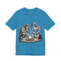 Aqua blue T-shirt featuring a graphic of a bearded caveman in a leopard-print pelt sitting by a campfire with a futuristic robot