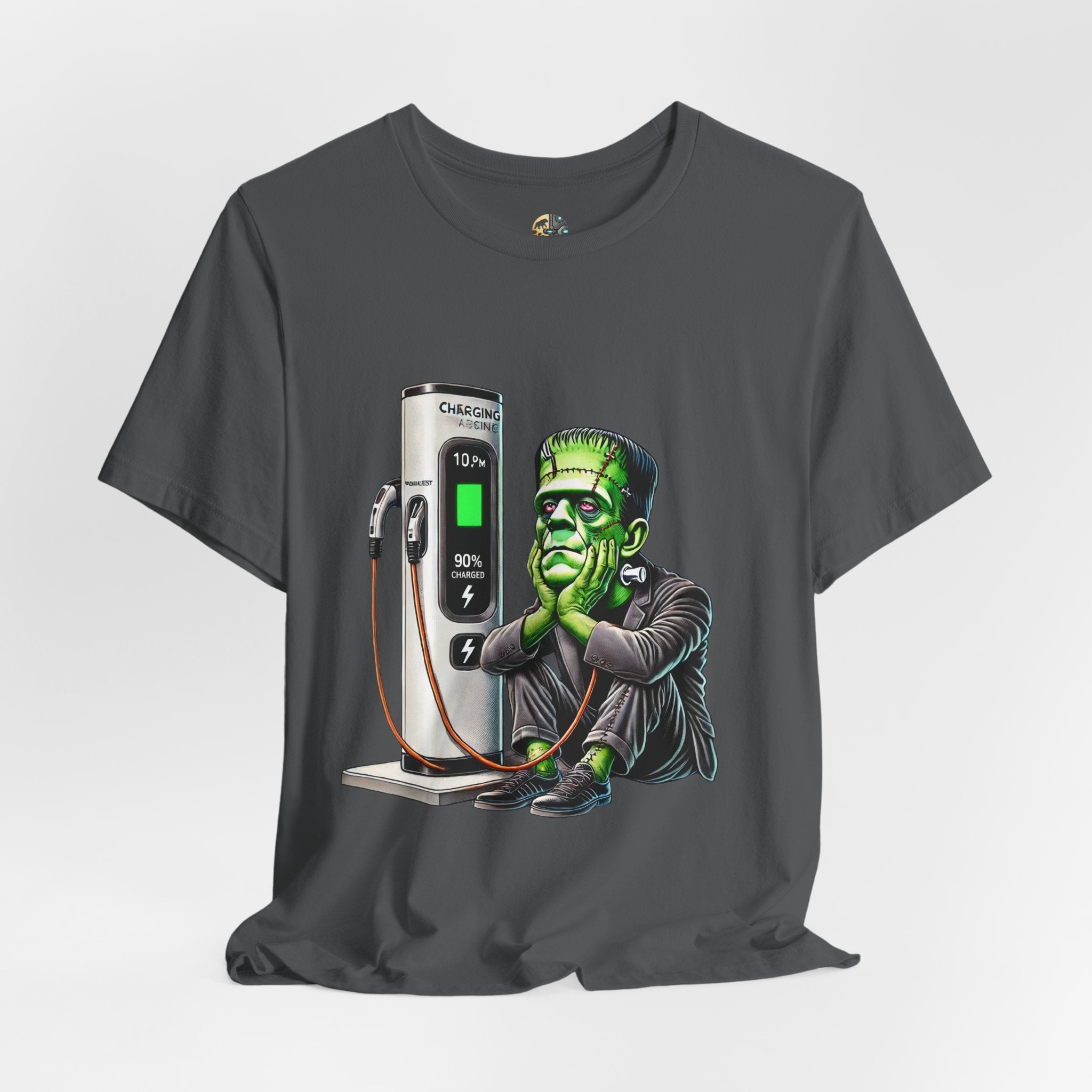 Asphalt grey T-shirt featuring a graphic of Frankenstein’s monster sitting at an electric charging station, plugged in and waiting for the charge to complete