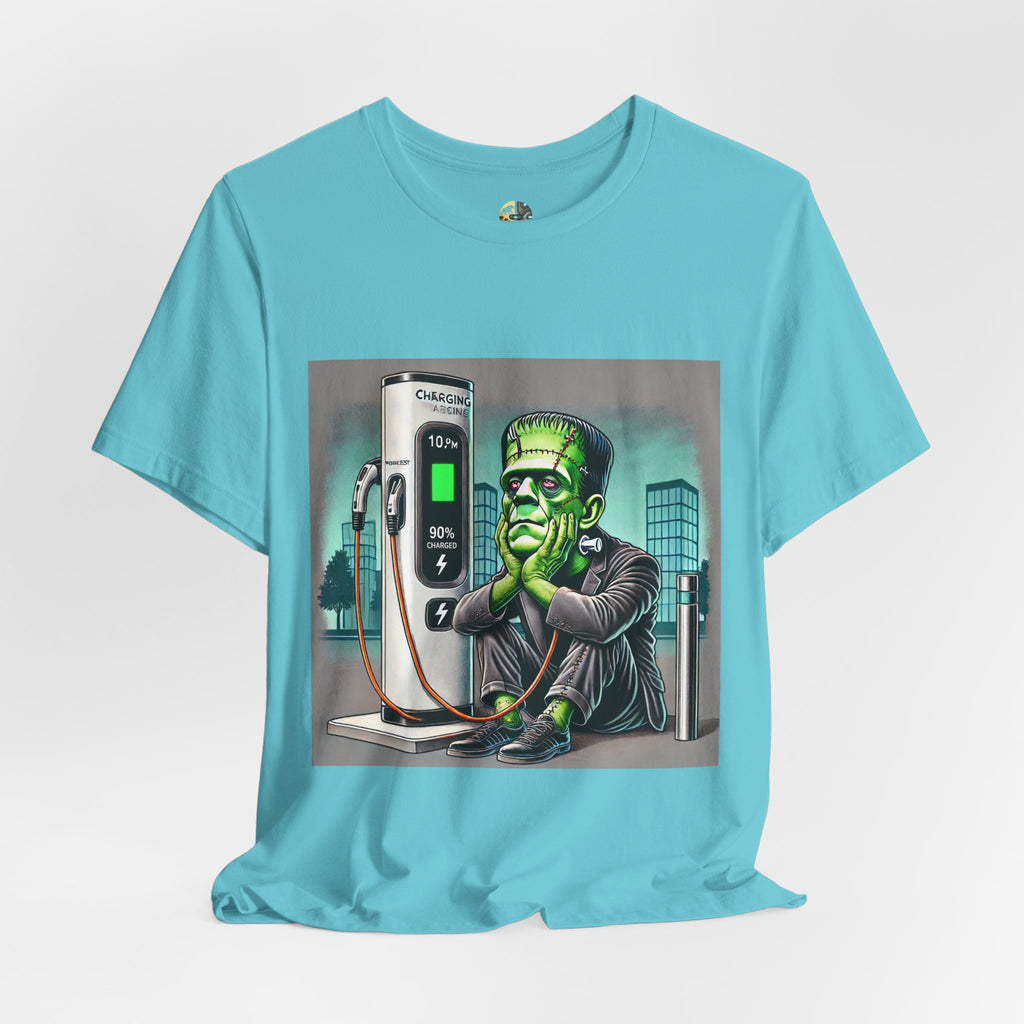 Turquoise T-shirt featuring a graphic of Frankenstein’s monster sitting at an electric charging station, plugged in and waiting for the charge to complete, with office buildings in the background