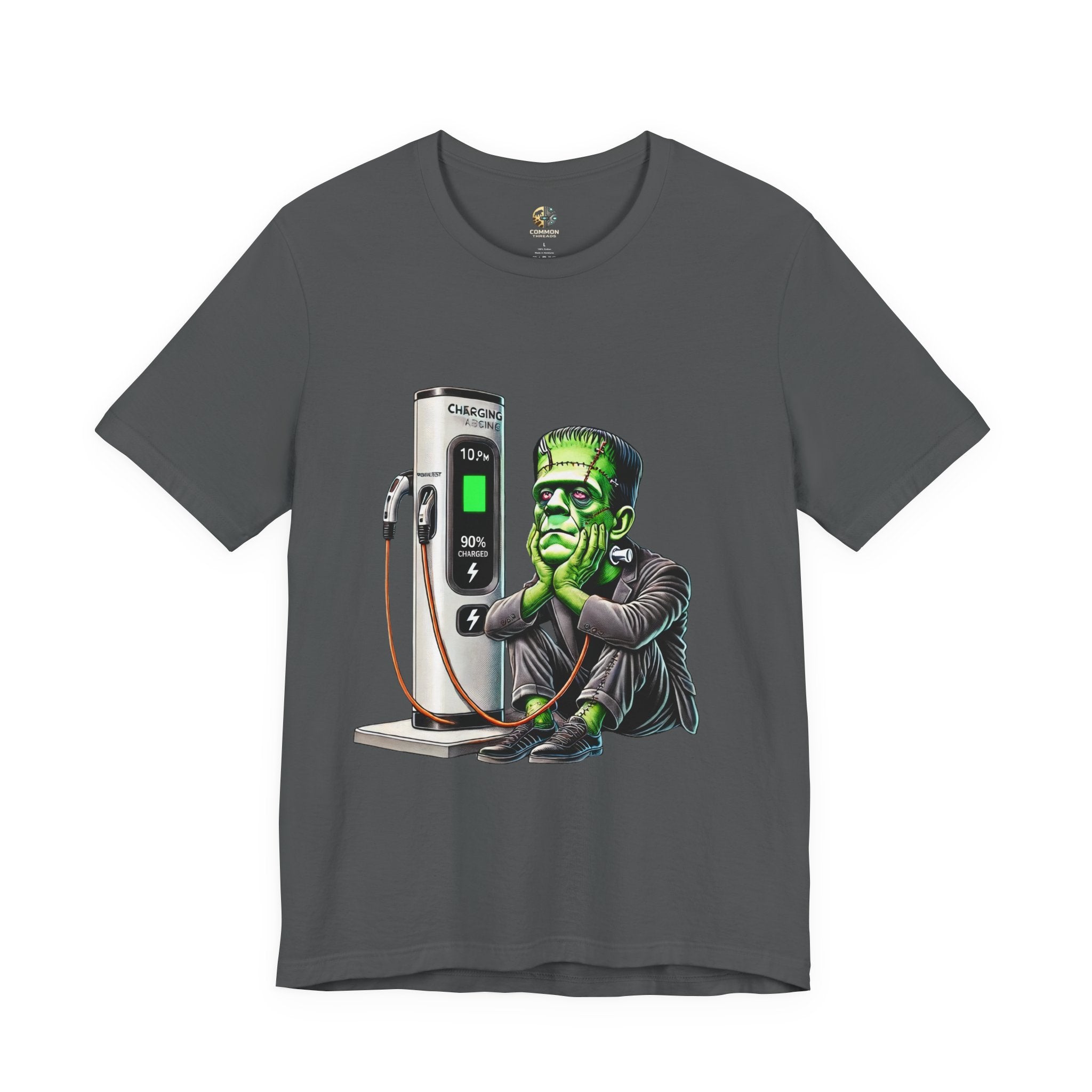 Asphalt grey T-shirt featuring a graphic of Frankenstein’s monster sitting at an electric charging station, plugged in and waiting for the charge to complete