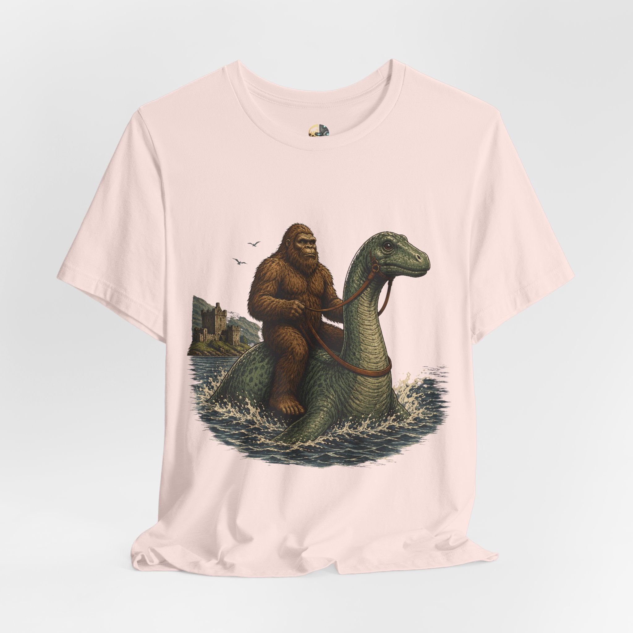 Soft pink t-shirt featuring bigfoot riding on the Loch Ness monster