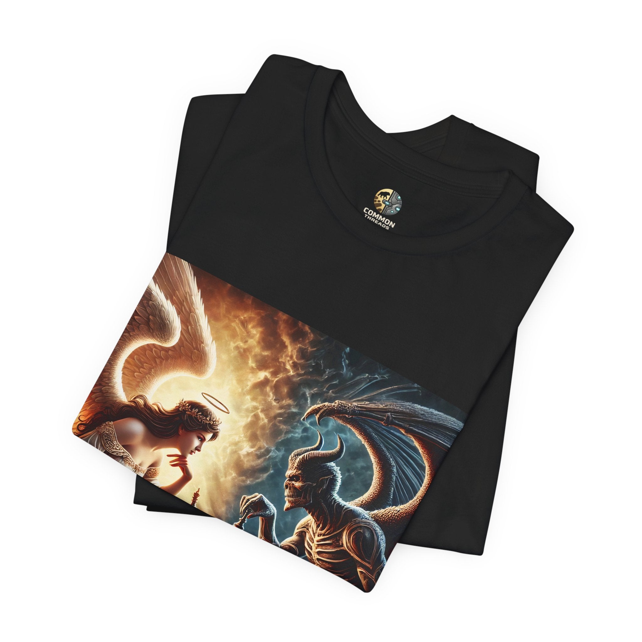 Folded black T-shirt featuring a graphic of an angel and a demon playing chess, with a golden king piece levitating, a dark background behind the demon and warm light tones behind the angel