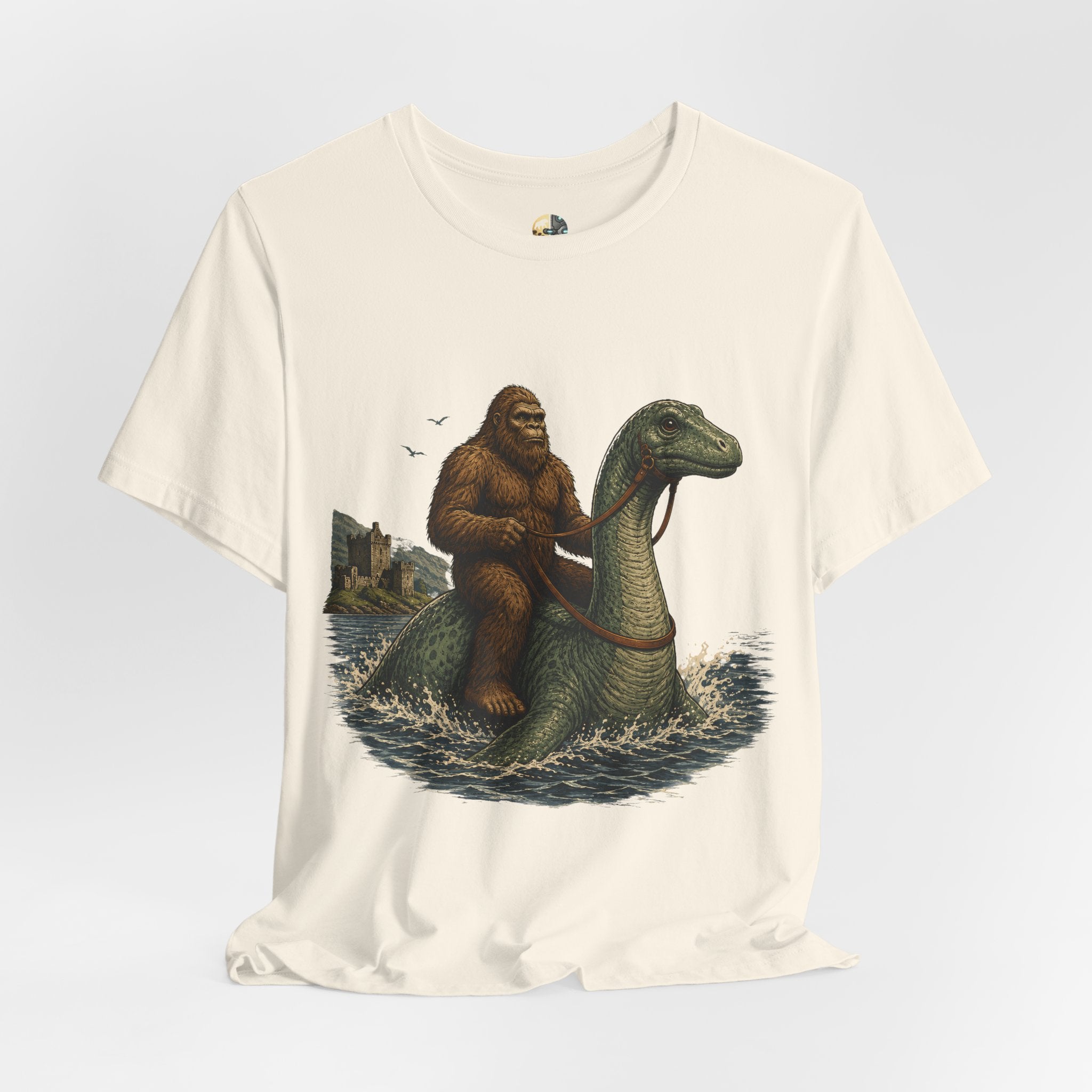 Natural color t-shirt featuring bigfoot riding on the Loch Ness monster