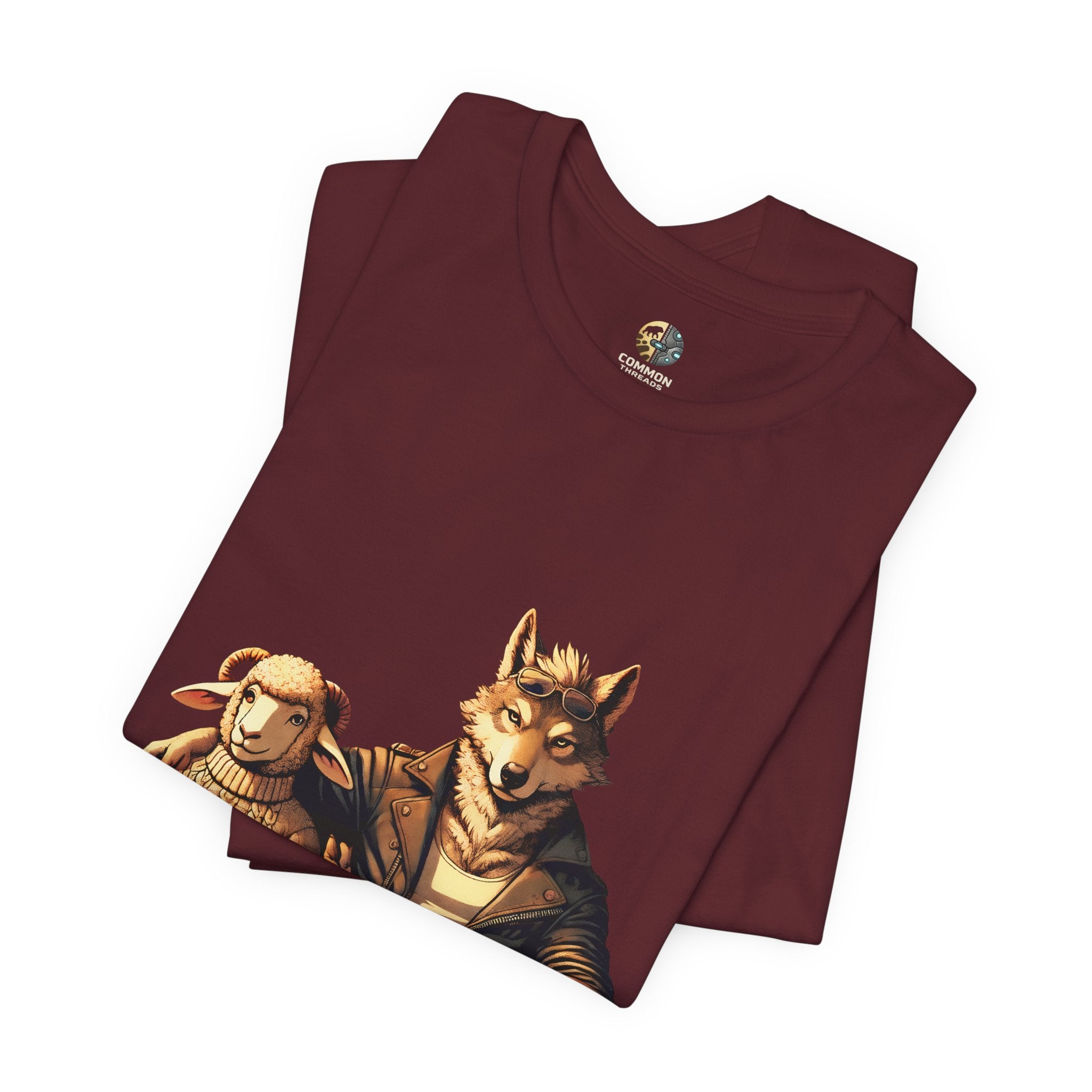 Folded maroon color T-shirt featuring an anthropomorphic wolf and lamb seated at a café table with coffee cups, illustrated in warm, painterly tones