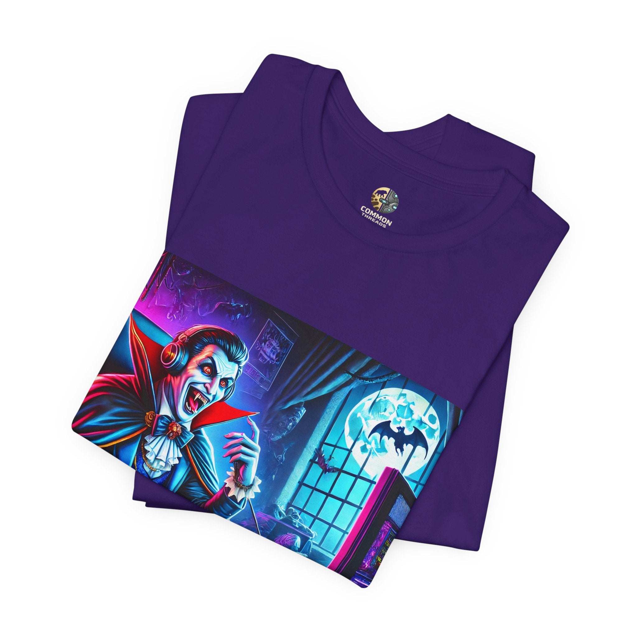 Folded purple T-shirt graphic of a classic vampire wearing a gaming headset and holding a controller at a neon-lit gaming setup under a full moon