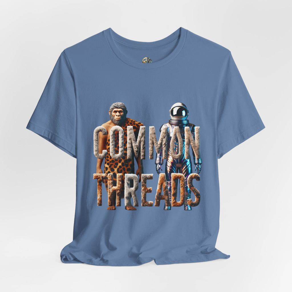 Lavender blue T-shirt featuring a graphic of a caveman in animal pelts standing beside a chrome-plated astronaut, with the text ‘Common Threads‘