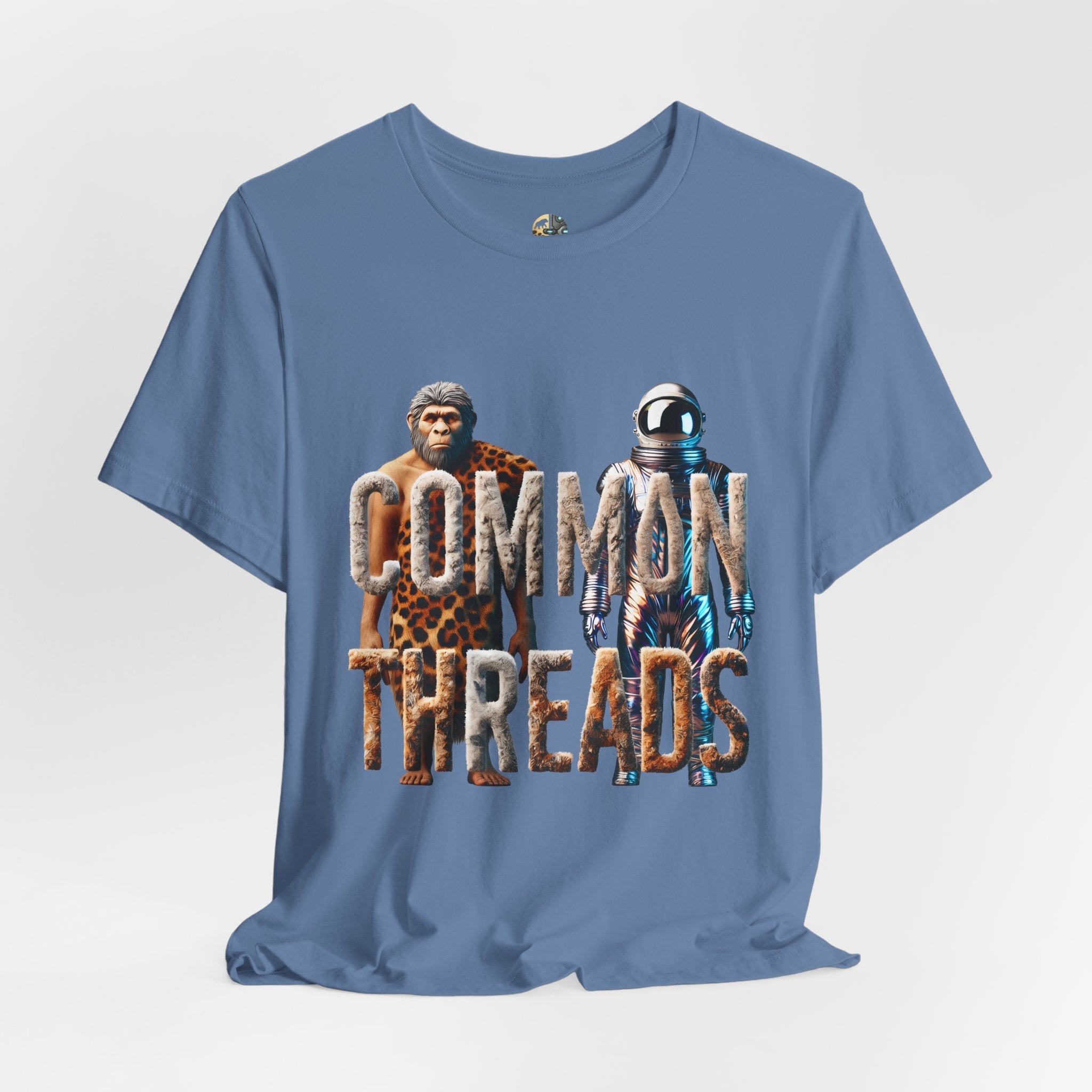 Lavender blue T-shirt featuring a graphic of a caveman in animal pelts standing beside a chrome-plated astronaut, with the text ‘Common Threads‘