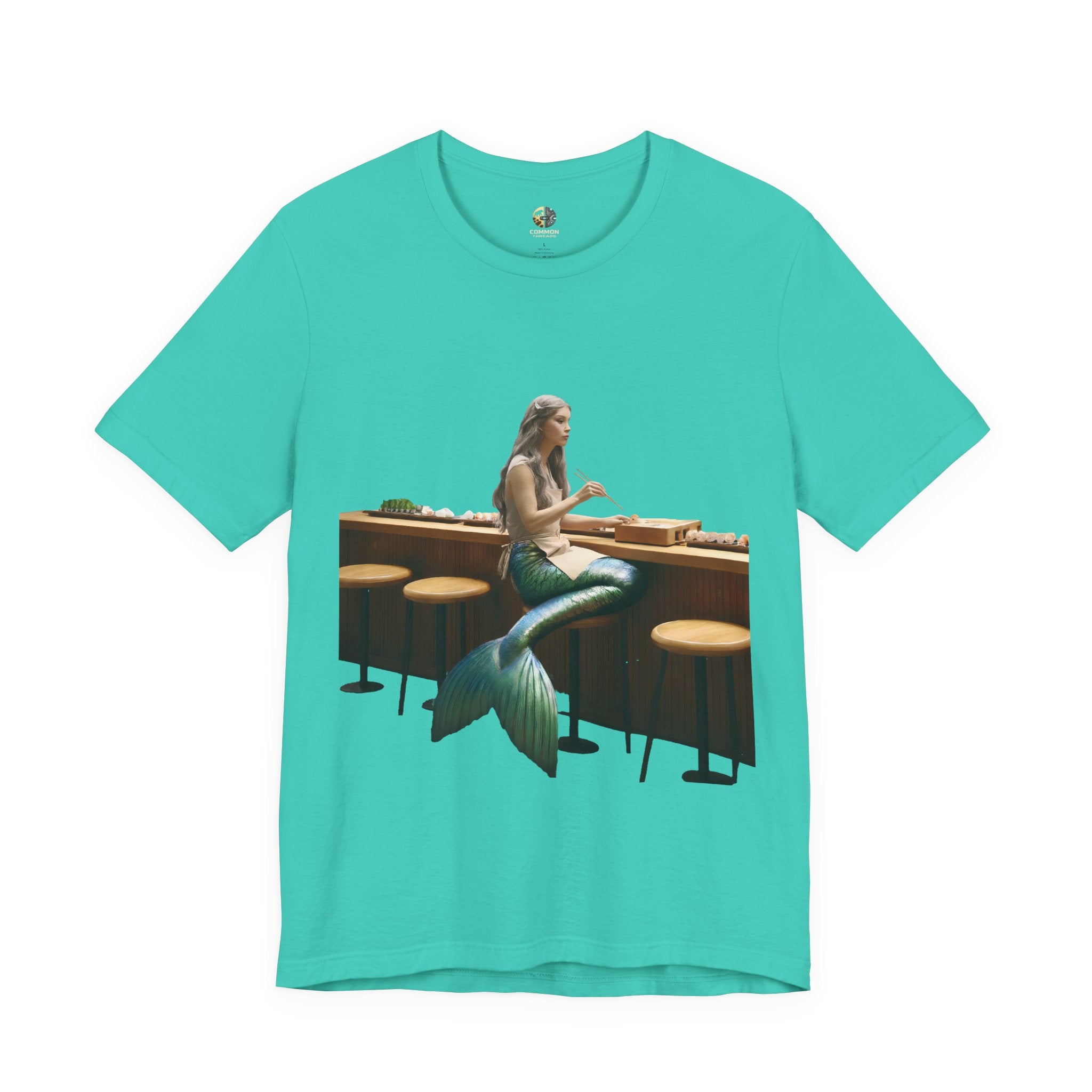 Teal T-shirt with graphic of a mermaid wearing a chef’s apron sitting at a sushi bar and eating sushi with chopsticks