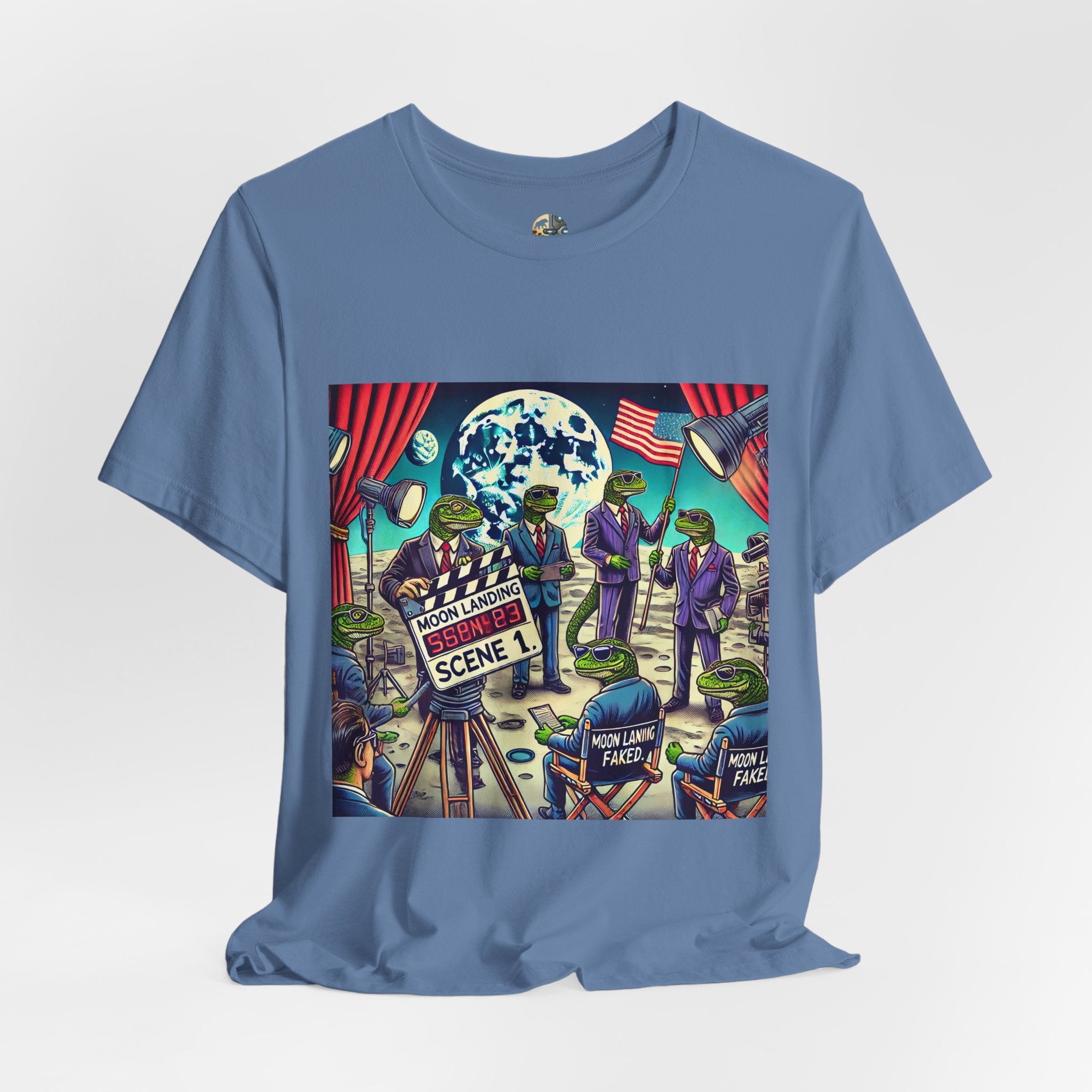 Lavender blue T-shirt featuring a graphic of lizard people in suits on a movie set staging a moon landing scene, with studio lights and a clapperboard