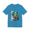 Aqua blue T-shirt featuring a graphic of Frankenstein’s monster sitting at an electric charging station, plugged in and waiting for the charge to complete