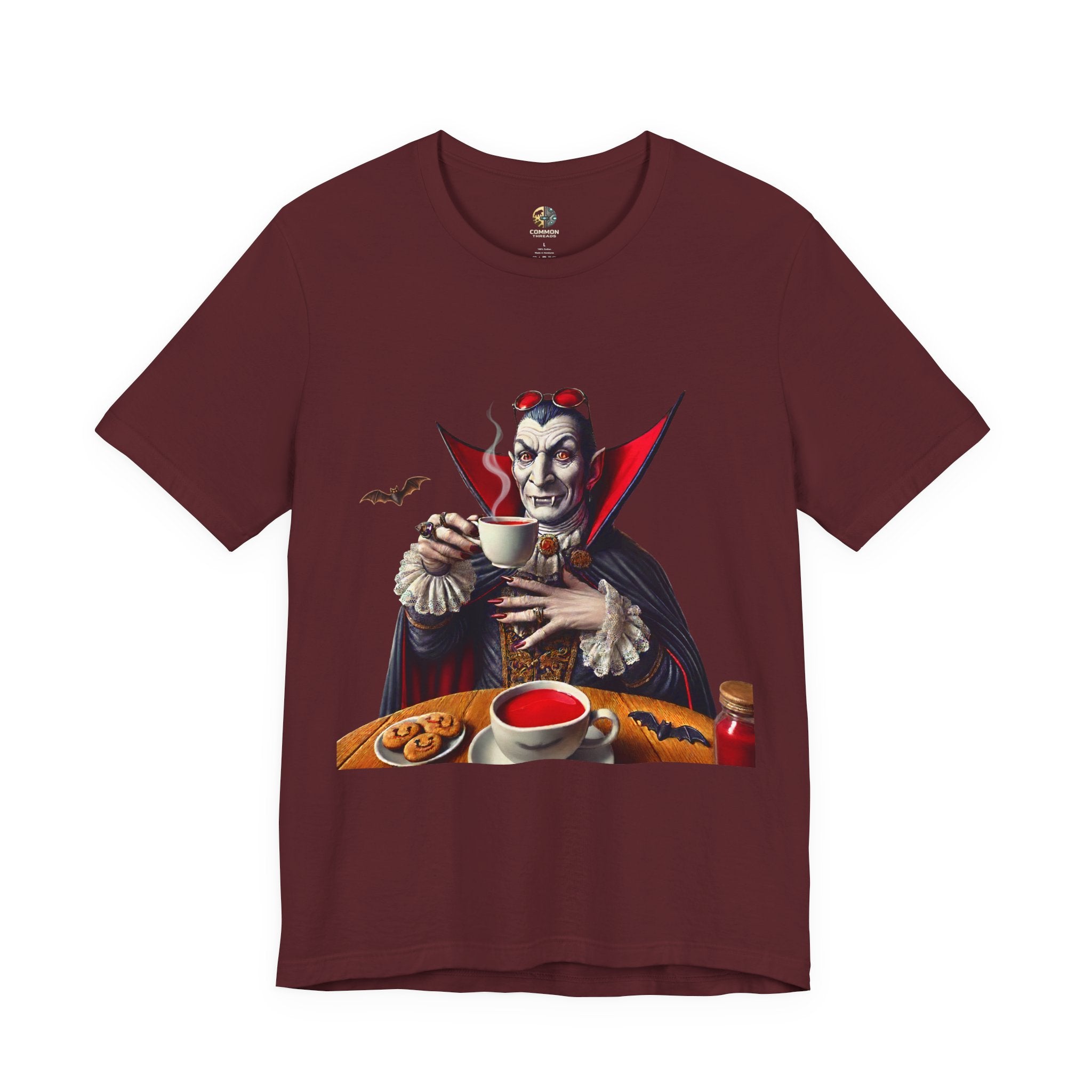 Maroon color T-shirt featuring a classic vampire dressed like Count Dracula sitting at a table, wearing red sunglasses and drinking from a teacup filled with red liquid