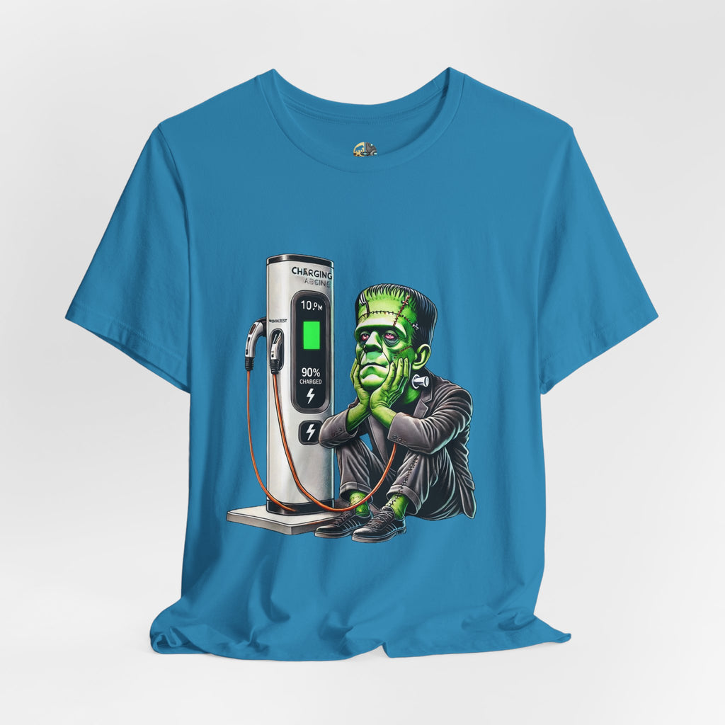 Aqua blue T-shirt featuring a graphic of Frankenstein’s monster sitting at an electric charging station, plugged in and waiting for the charge to complete