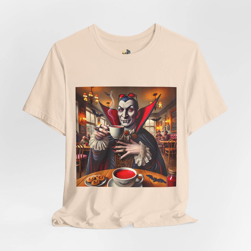 Soft creme T-shirt featuring a classic vampire dressed like Count Dracula sitting in a café, wearing red sunglasses and drinking from a teacup filled with red liquid