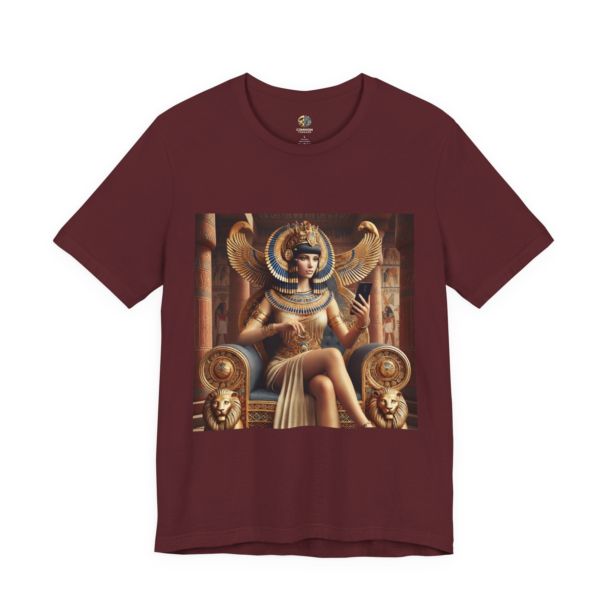 Maroon color T-shirt featuring a graphic of Cleopatra wearing an ornate headdress and gold jewelry, seated on a throne and holding a smartphone for a selfie, with temple architecture in the background