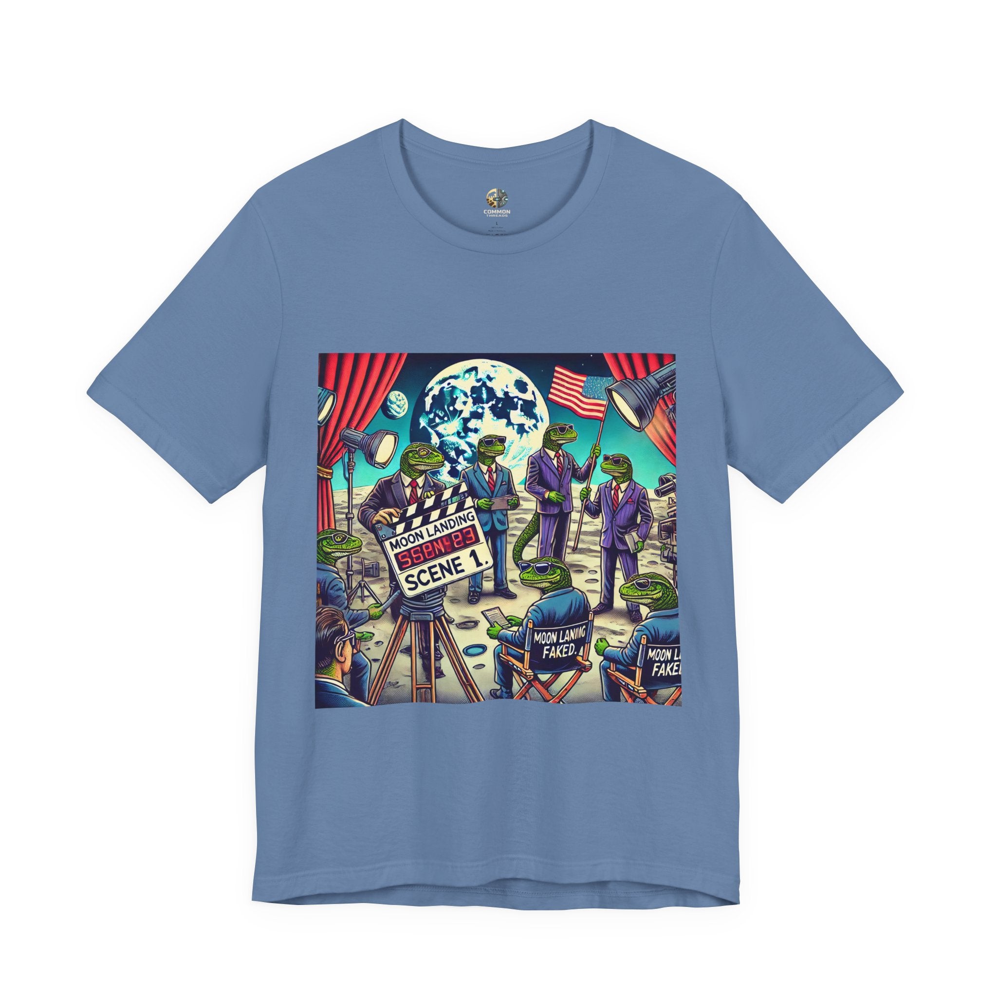 Lavender blue T-shirt featuring a graphic of lizard people in suits on a movie set staging a moon landing scene, with studio lights and a clapperboard